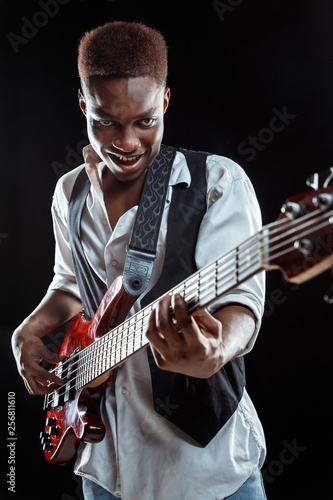 Canvas Print African American handsome jazz musician playing bass guitar in the studio on a black background