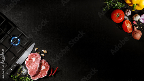 Fresh rare beef steak on a black stone with chef knife and cooking surface. With tomatoes, sweet and spicy peppers, greens and spices, white salt and black pepper. 