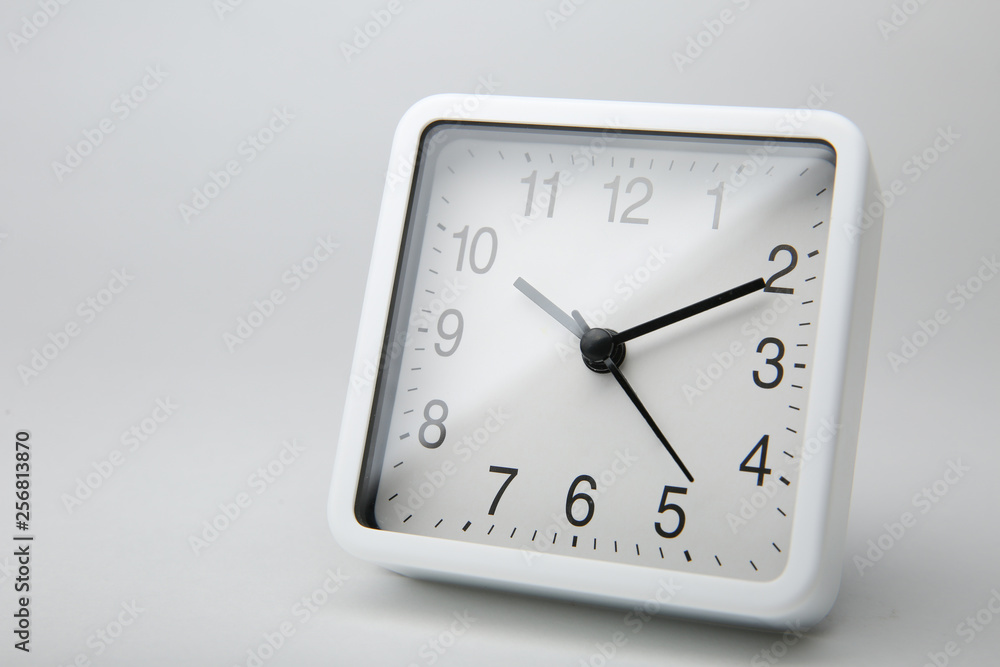 white square clock alarm clock isolated on white background. plastic clock with black clock hands. ten past ten white square clock alarm clock isolated on white background. plastic clock with black clock hands. ten past ten
