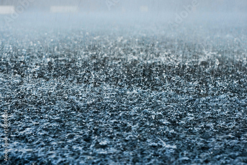 Drops of heavy rain in a puddle on the asphalt road. A Stream of water that floods all around. Macro Photography