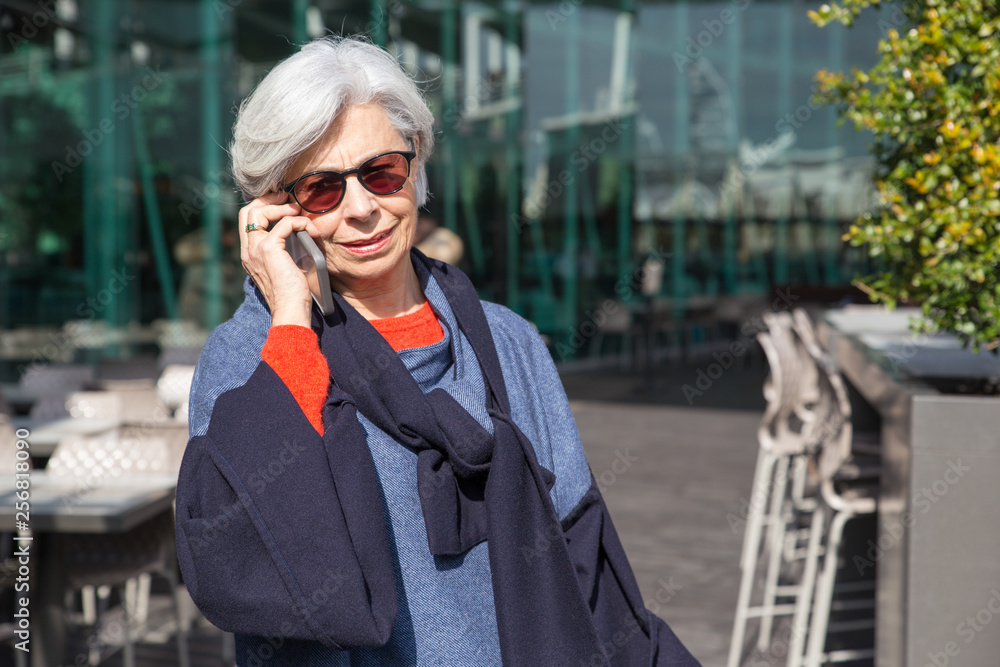 Fototapeta premium Smiling senior woman talking on smartphone outdoors