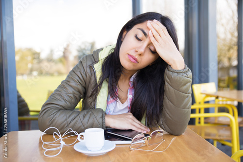 Lady touching forehead and relaxing in outdoor cafe