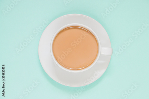 Cup of coffee with milk on a colored background, top view