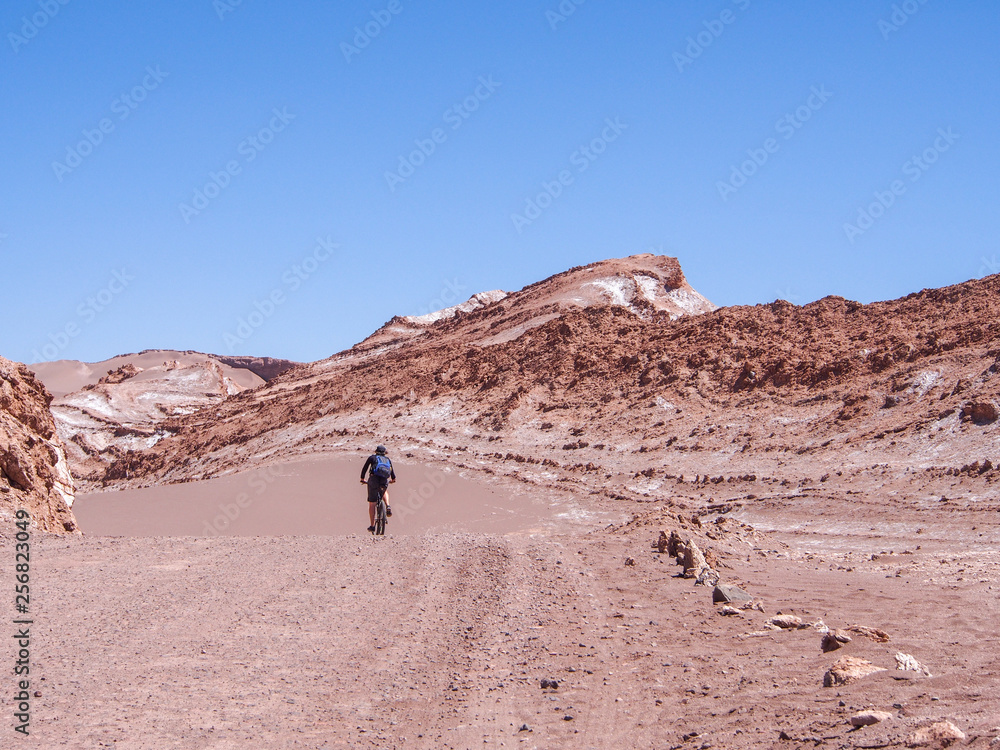 Cyclist on a lonely dust road in Valle de la Luna, San Pedro de Atacama, Chile