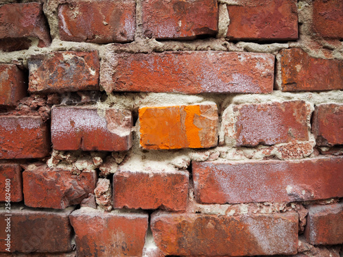 Brick wall with one bright orange brick in the center