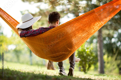 Back view of young man and girl in hammock