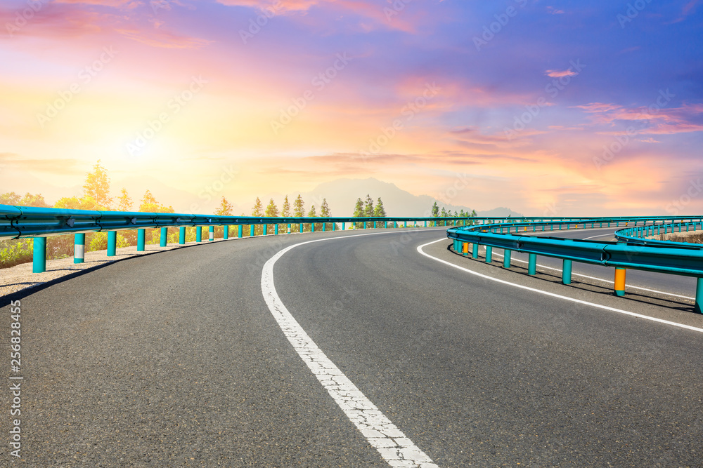 Fototapeta premium Asphalt highway and forest with mountain scenery at sunset