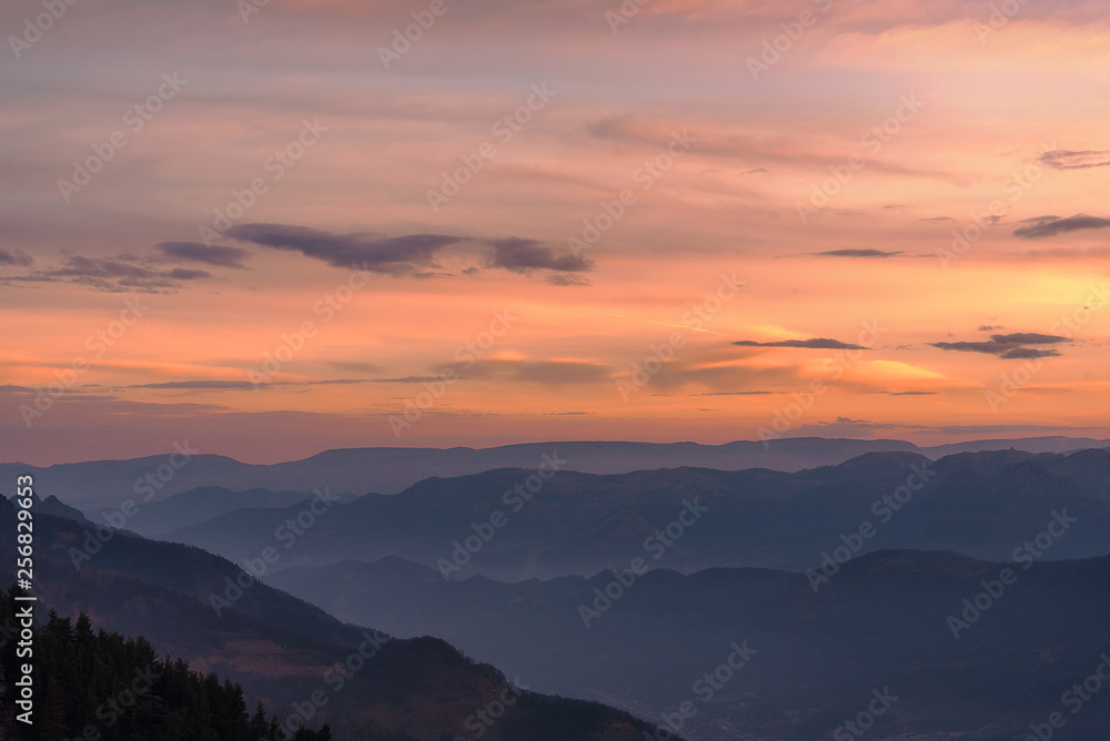 dawn sky in bright clouds above a mountain valley