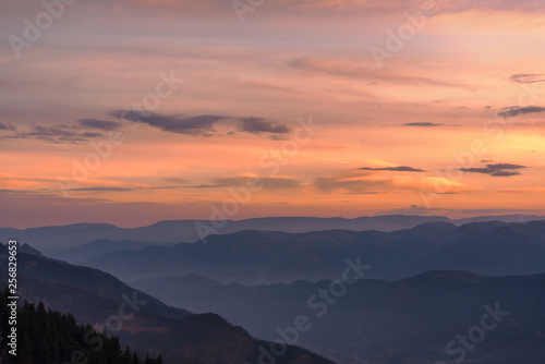 dawn sky in bright clouds above a mountain valley