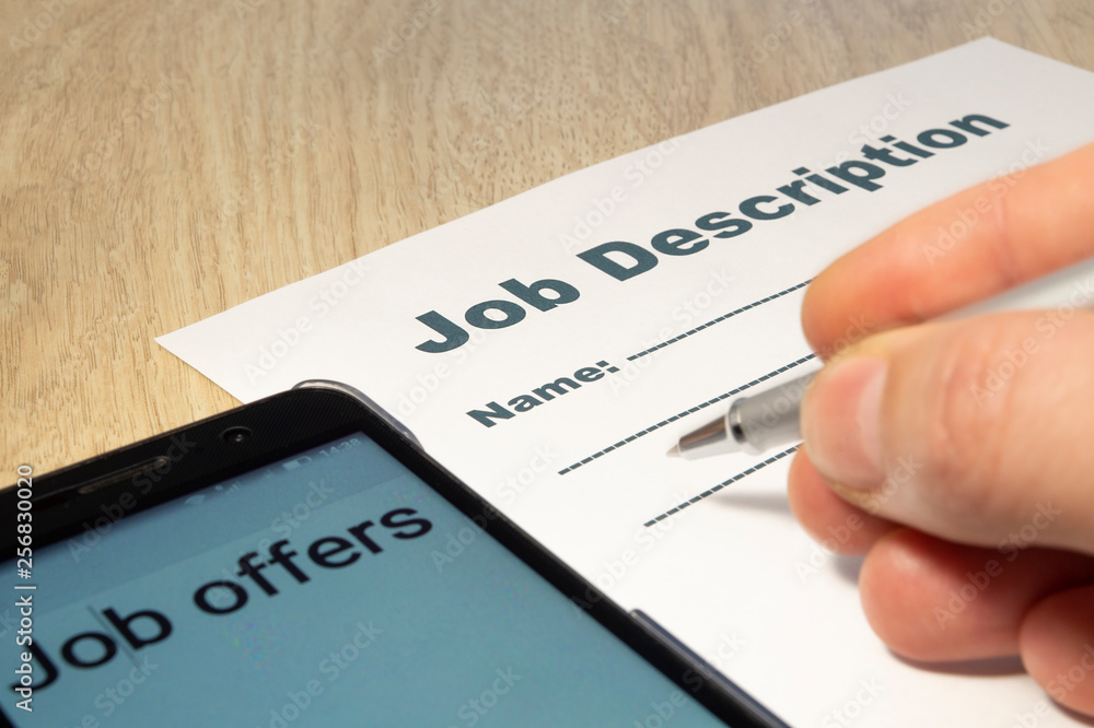 Job Description with Hand, smartphone and Pen on the table. Job Description with Hand, smartphone and Pen on the table.