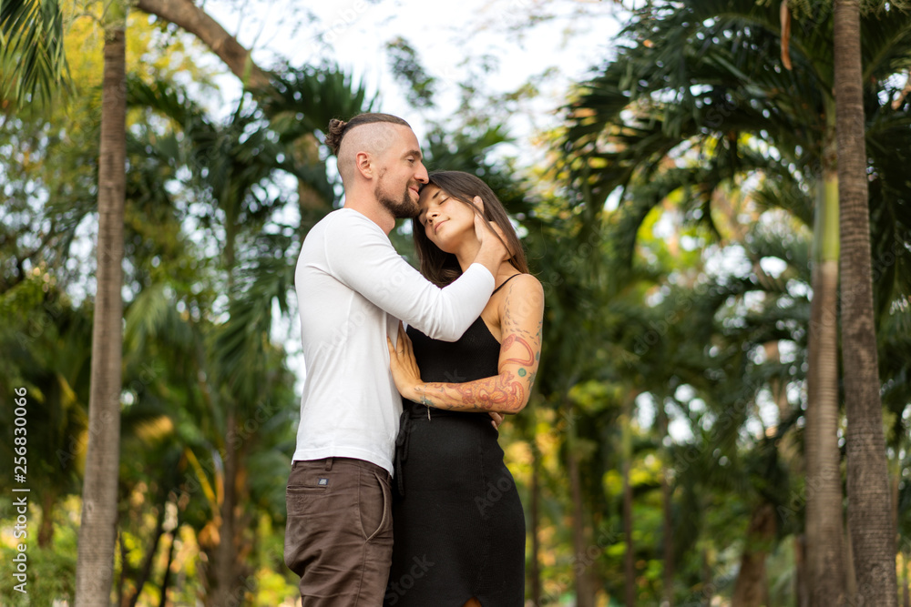 Couple in love laughing looking at each other in the Bangkok park and tropical threes Couple in love laughing looking at each other in the Bangkok park and tropical threes