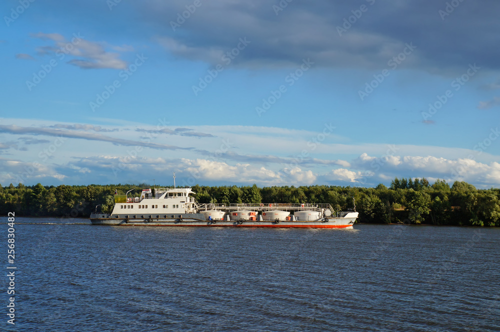 Cargo ship goes along the Volga river, Russia. Bright sunny summer evening