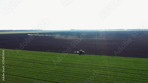 Aerial view of the spring plowing of an agricultural field with a tractor with a cultivator and a column of dust at sunset. Soil preparation on the field of agricultural equipment. Texture brown soil photo