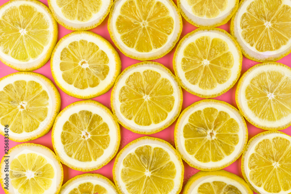Pattern made from fresh lemon slices on a pink background, overhead view, flatlay. Fruit background.