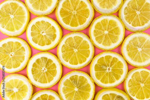 Pattern made from fresh lemon slices on a pink background, overhead view, flatlay. Fruit background.