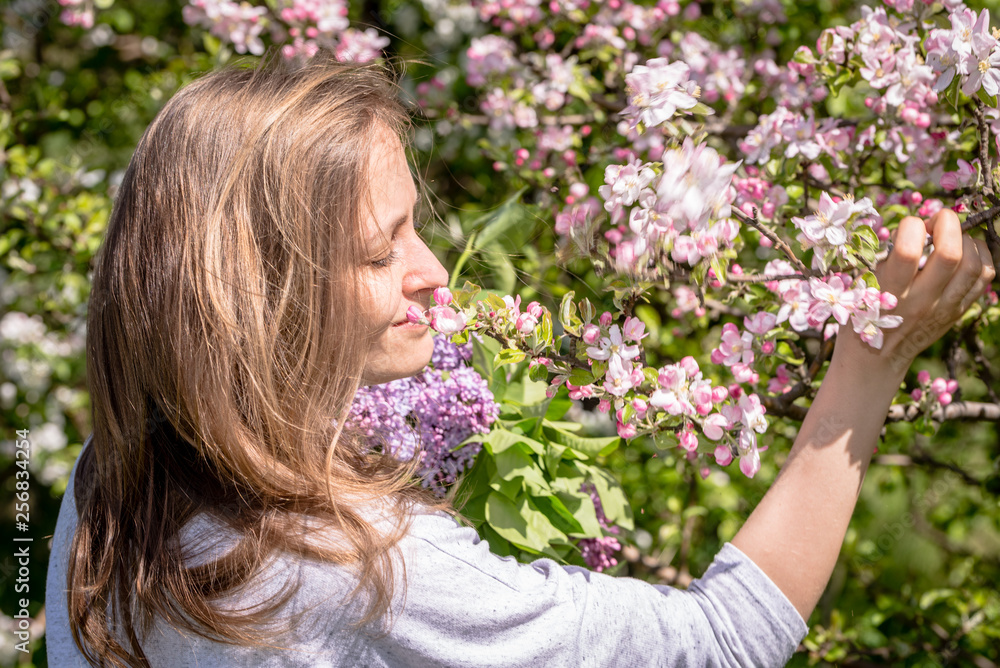 Fototapeta premium Beautiful woman among spring blossoming apple trees in orchard