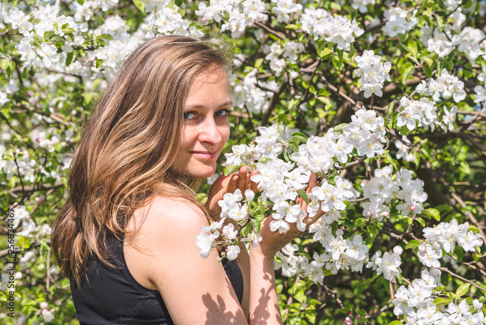 Beautiful woman among spring flowering apple trees in orchard Beautiful woman among spring flowering apple trees in orchard