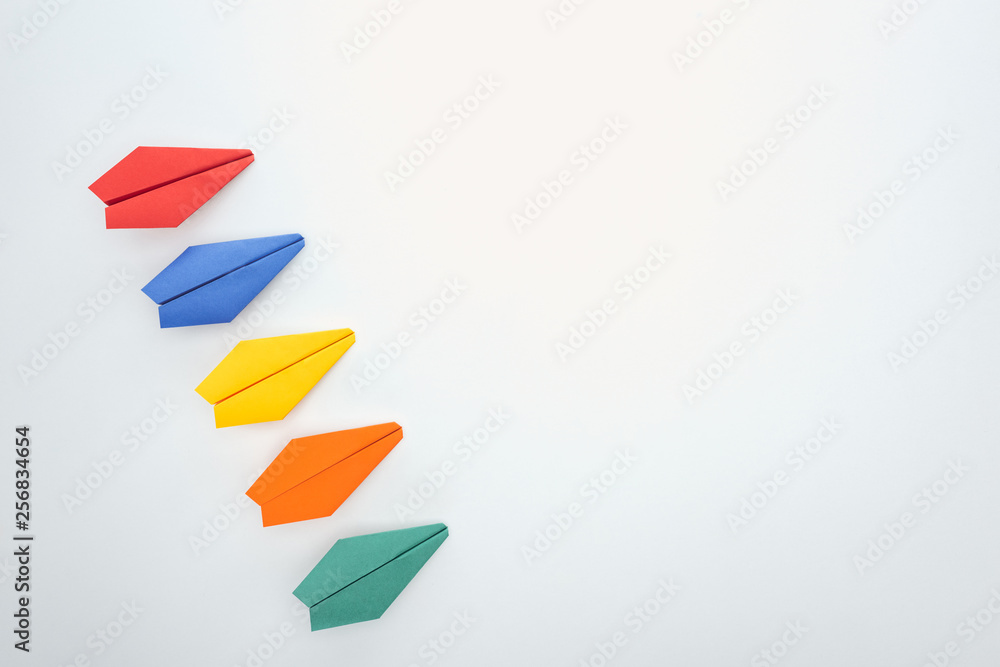 Flat lay with colorful paper planes on white surface Flat lay with colorful paper planes on white surface