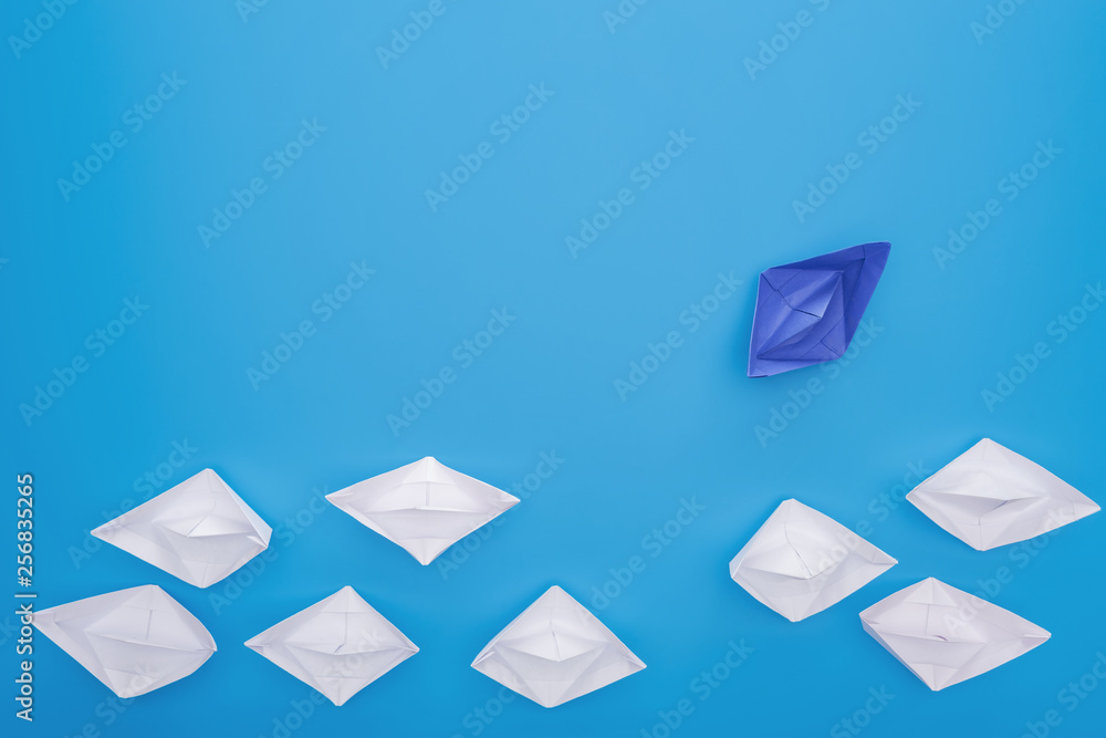 Flat lay with white and blue paper boats on blue