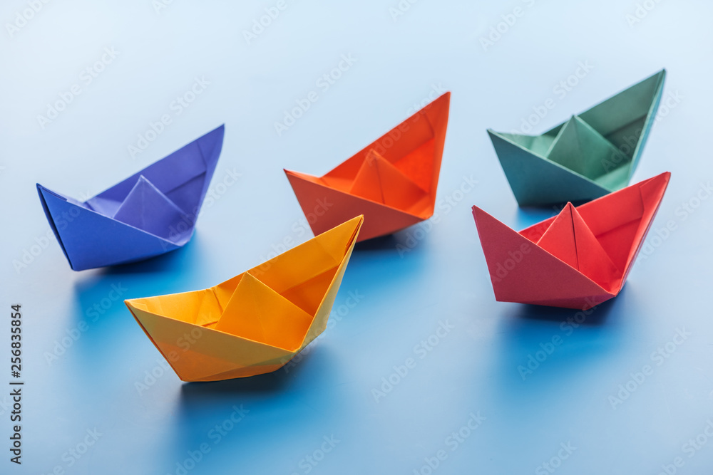 Colorful bright paper boats on light blue surface Colorful bright paper boats on light blue surface