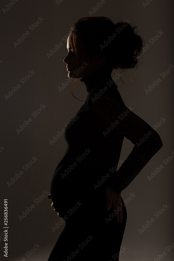 Close Up of pregnant woman's belly, side view. silhouette of Pregnant woman on a black background Close Up of pregnant woman's belly, side view. silhouette of Pregnant woman on a black background
