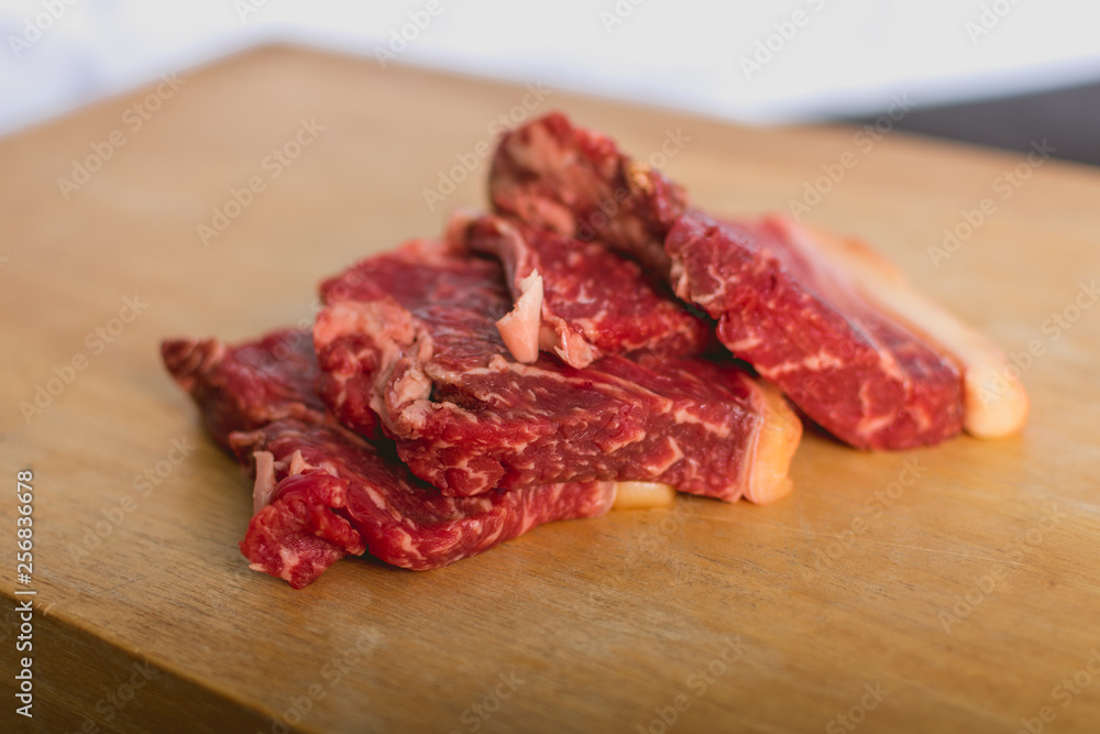 fresh raw beef meat steak slices on wooden cut board over white background