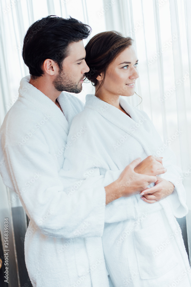 happy couple in white bathrobes hugging in hotel happy couple in white bathrobes hugging in hotel