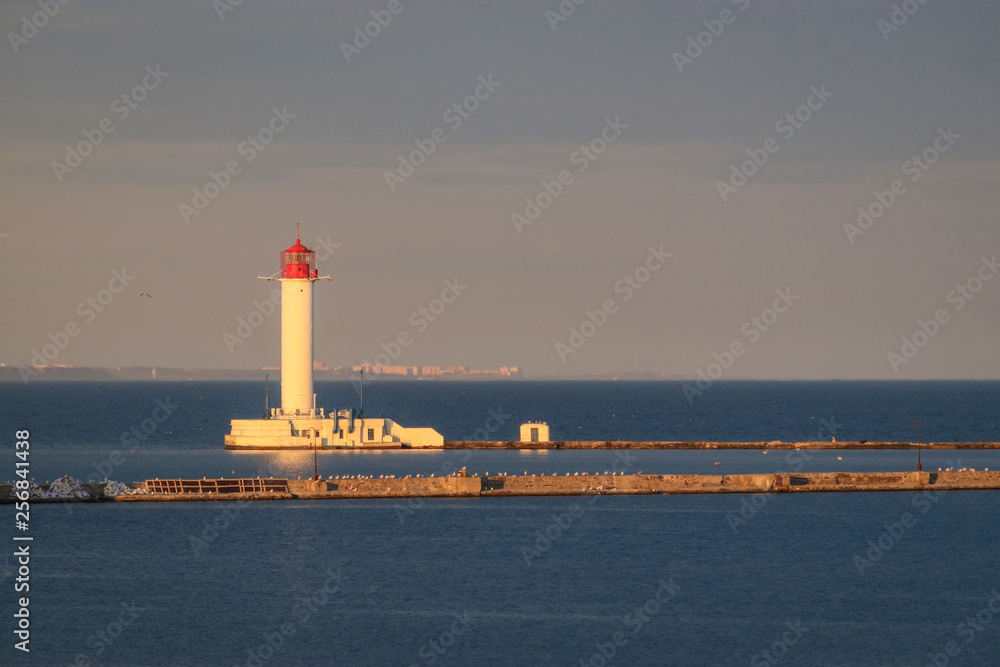 white lighthouse on  against the background of the sea and dark sky in the evening.