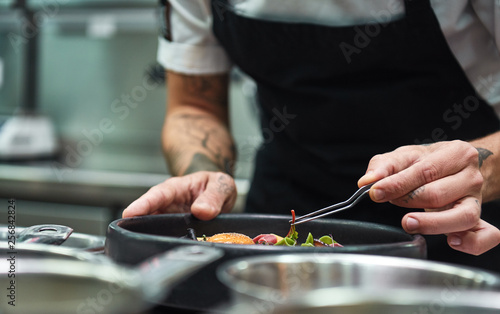 Creative Cooking. Cropped image of chef hands garnishing Pasta carbonara in a restaurant kitchen.