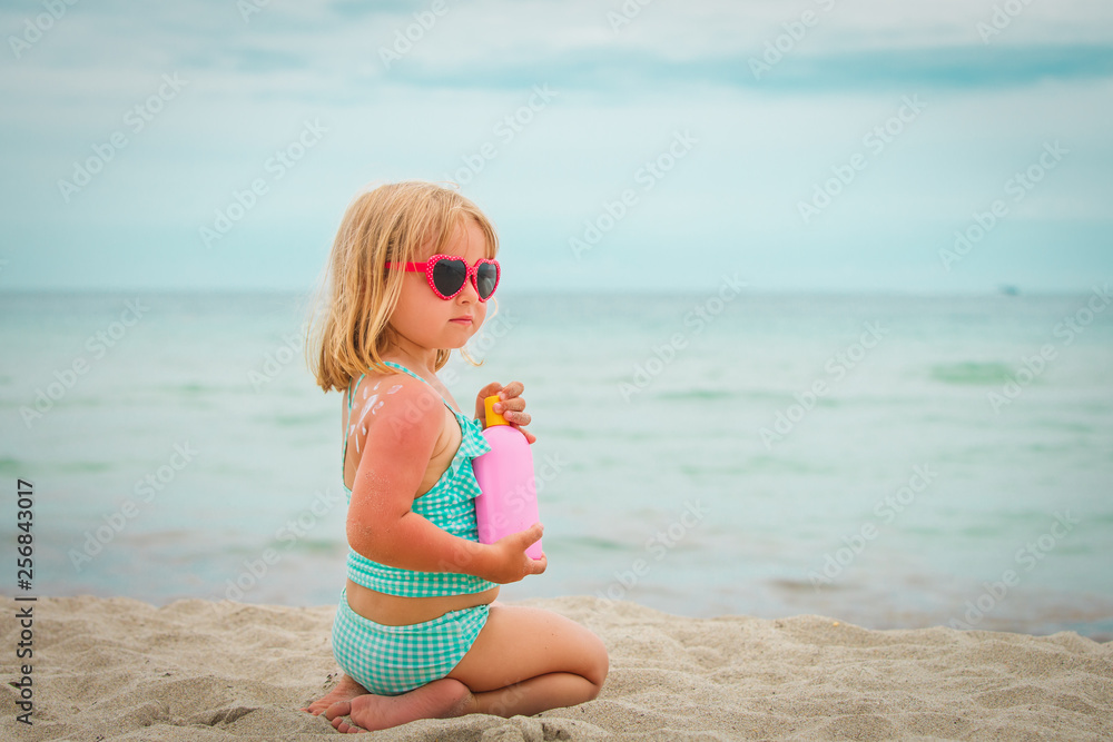 sun protection concept - little girl with suncream at beach sun protection concept - little girl with suncream at beach