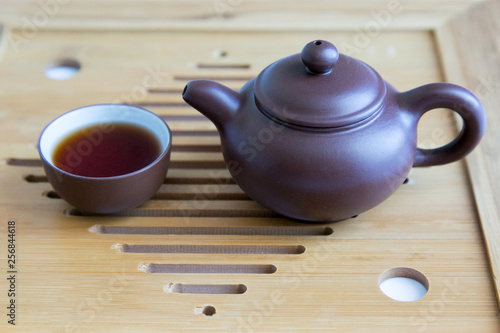 Miniature antique tableware for tea on a wooden tray. Teapot and cup made of clay on a wooden background