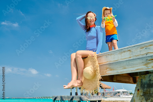 Toddler boy with mother sitting on wooden jetty