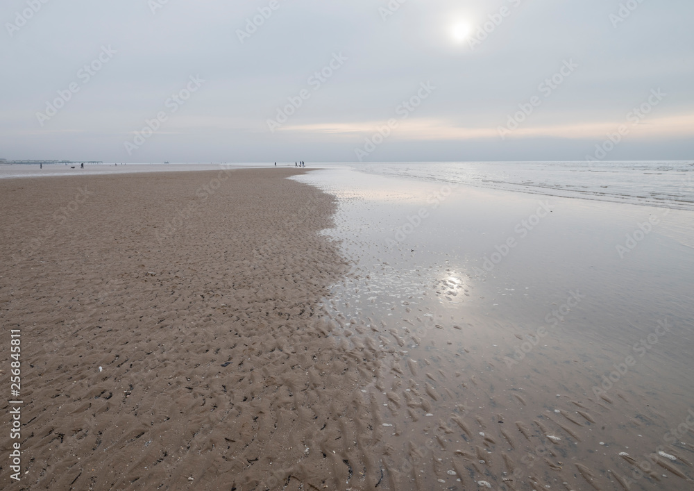 Obraz premium Watery sunlight in the winter on the Fylde shore at Lytham St. Anne's on the Lancashire coast, England UK. Lovely muted colours and reflections.