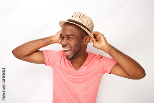 cheerful young african american man laughing with hat against white background
