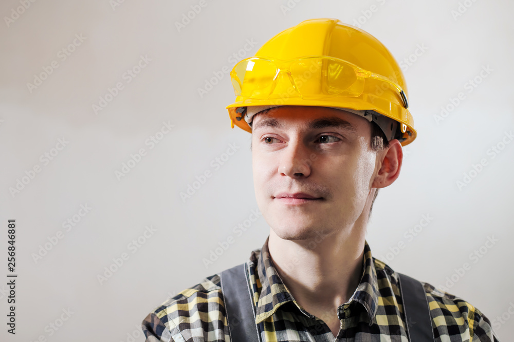 Portrait of a young male builder and repairman in a yellow helmet against the background of a wall. Portrait of a young male builder and repairman in a yellow helmet against the background of a wall.