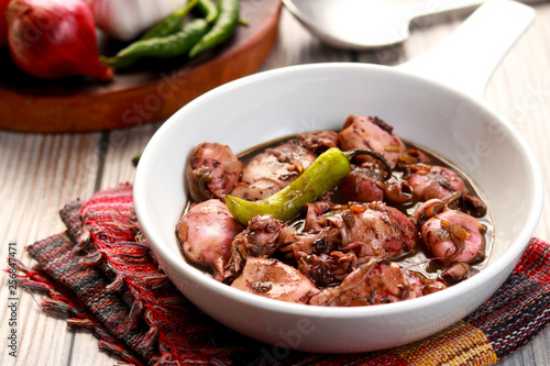 A tasty squid dish with soy sauce in white bowl. Adobong Pusit from Philippines.