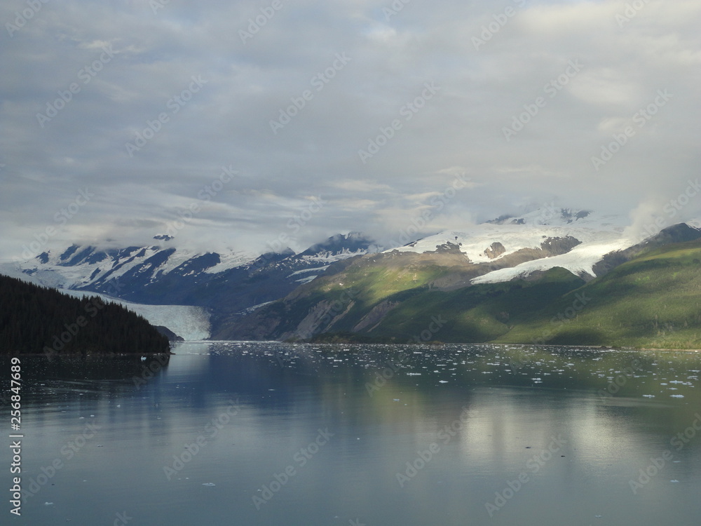 Oceanside Mountains with Glaciers sliding into the Pacific Ocean. Snow capped peaks under a heavily clouded sky