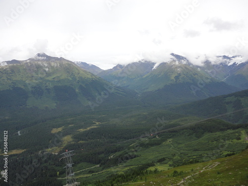 View from atop a mountain in the wilderness of Alaska. Peaks and ocean stretching off into the sky and clouds © Justin