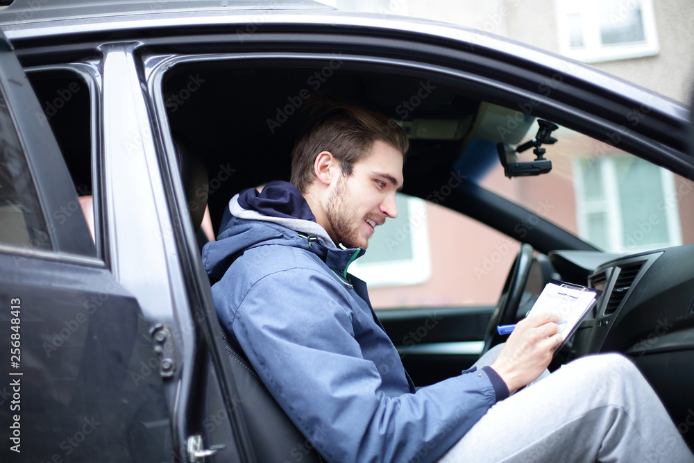 man signs a document while sitting in the car man signs a document while sitting in the car