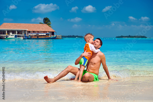 Toddler boy on beach kissing father