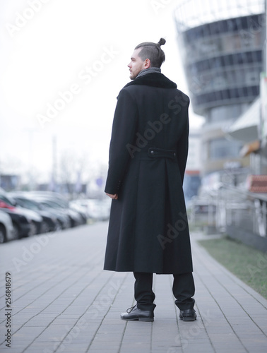 young business man in a winter coat standing on the street