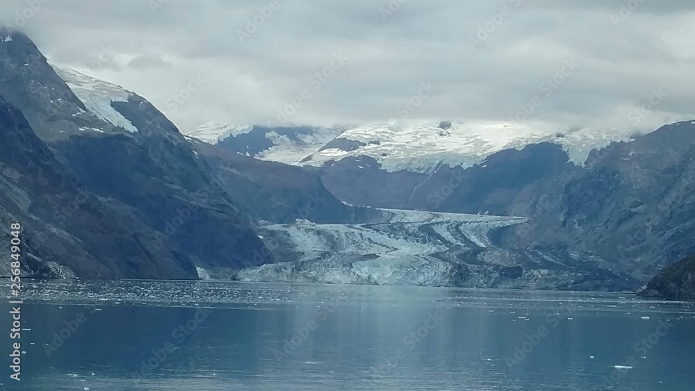Glaciers within Glacier Bay National Park in Alaska. Glaciers coming over mountain peaks and sliding into the Pacific Ocean