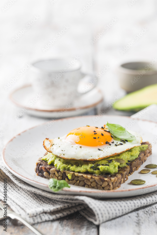 Sandwich with avocado, egg and spinach on white wooden background. Healthy diet breakfast Sandwich with avocado, egg and spinach on white wooden background. Healthy diet breakfast