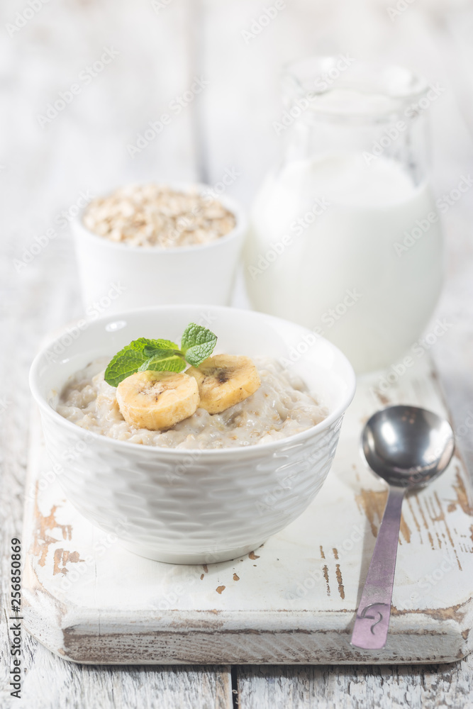 Bowl of oatmeal porridge with banana on white wooden rustic table, healthy breakfast, diet food. Bowl of oatmeal porridge with banana on white wooden rustic table, healthy breakfast, diet food.