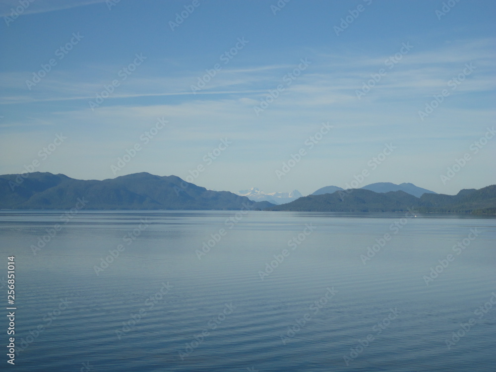 Passage in the Pacific Ocean between two mountain ranges. Calm peaceful waters flowing slowly under a cloudy sky.