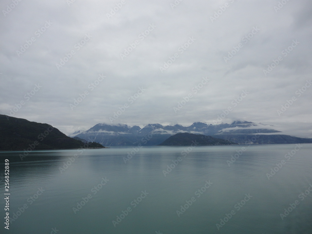 Mountain Filled horizon on the pacific ocean. Inside passage Alaska with glaciers at the peaks under a cloudy sky