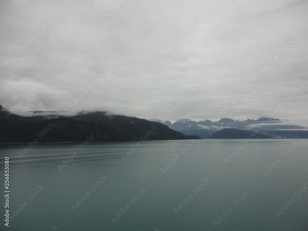 Mountain Filled horizon on the pacific ocean. Inside passage Alaska with glaciers at the peaks under a cloudy sky