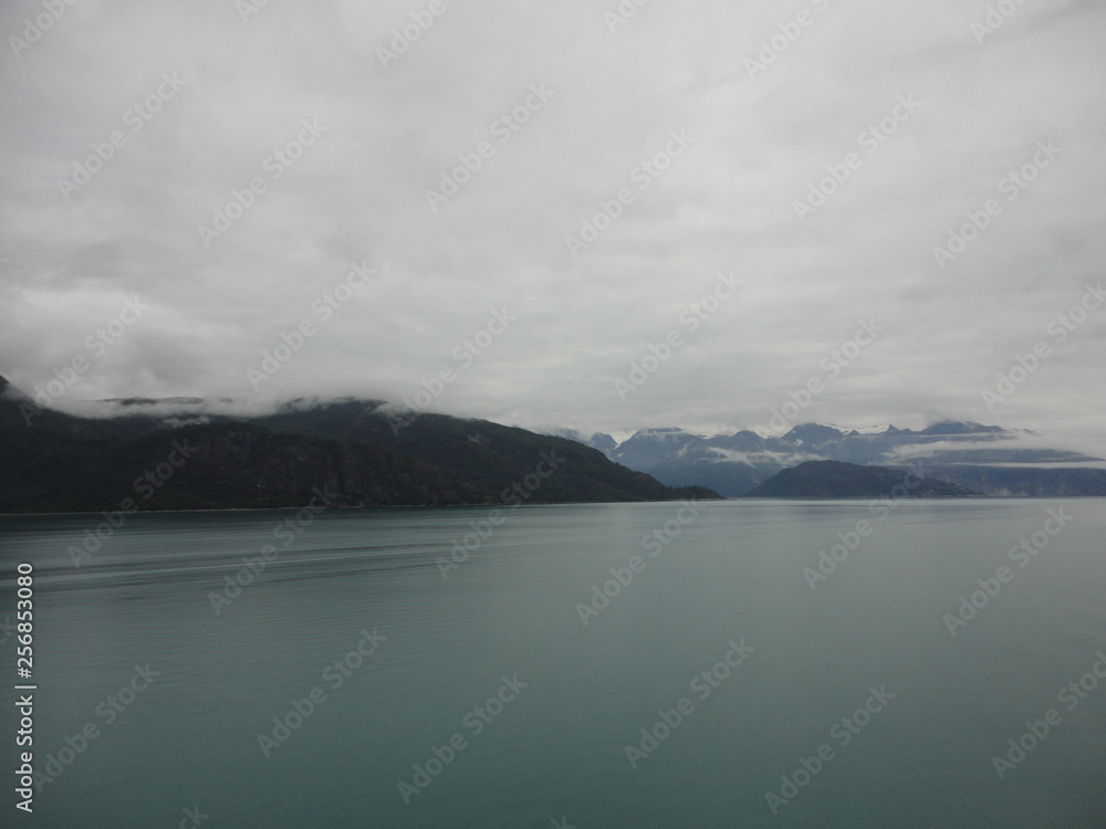 Mountain Filled horizon on the pacific ocean. Inside passage Alaska with glaciers at the peaks under a cloudy sky Mountain Filled horizon on the pacific ocean. Inside passage Alaska with glaciers at the peaks under a cloudy sky