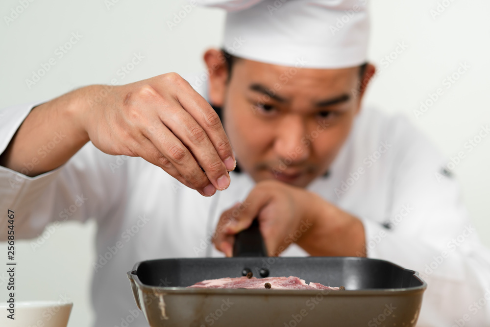Chef spreading black peppers on meat for preparing food. Chef spreading black peppers on meat for preparing food.
