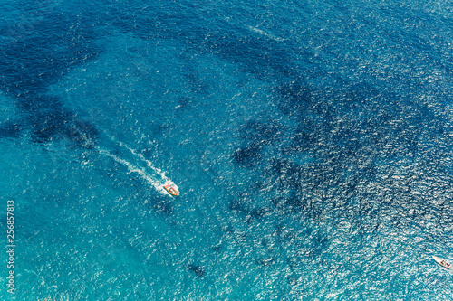 Yacht at the sea in Italy. Aerial view of luxury floating boat on transparent turquoise water at sunny day. Summer seascape from air. Top view from drone. Seascape with motorboat in bay.